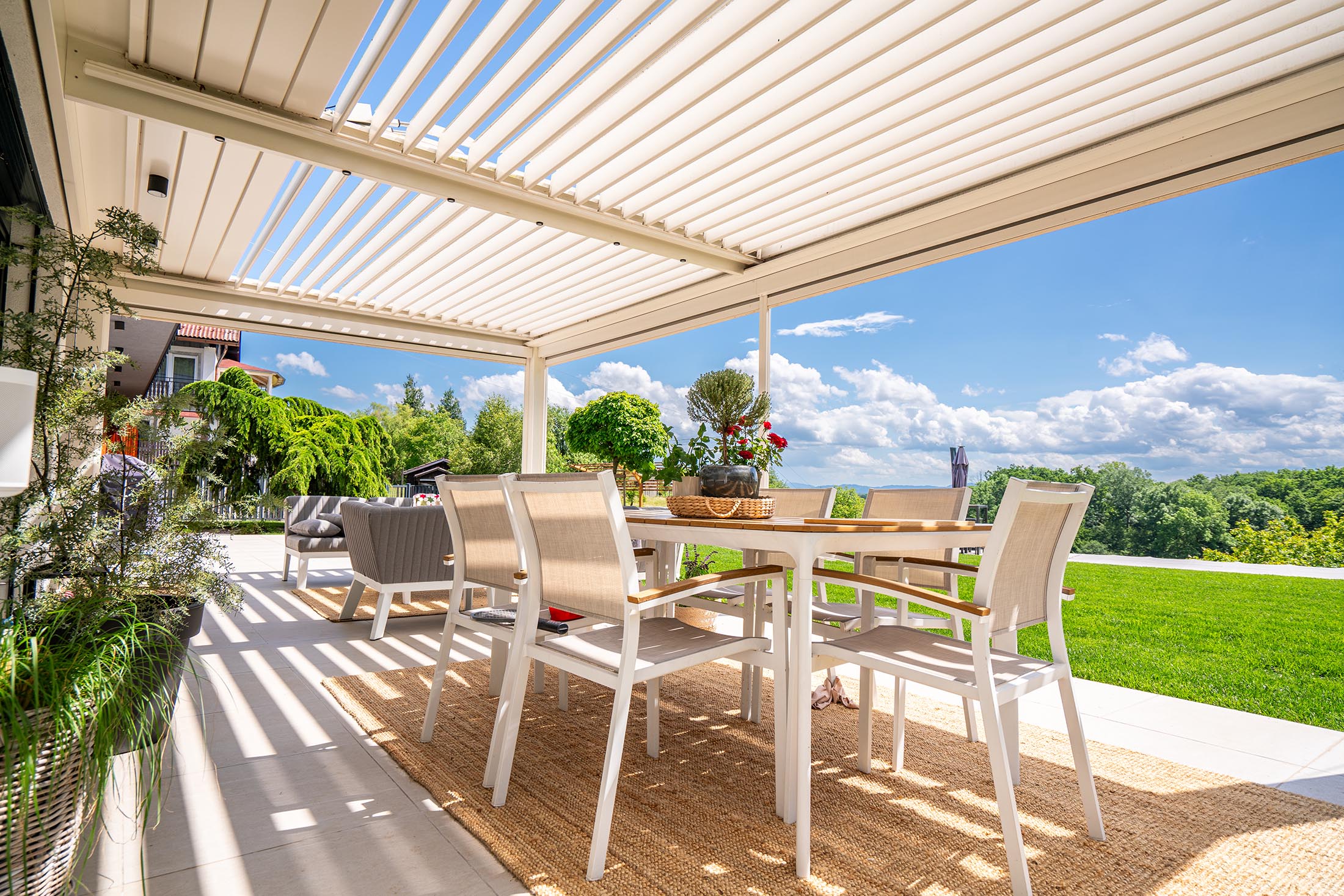 Bioklimatska pergola z dodatki na veliki terasi, ki omogoča popolno prilagodljivost in udobje na prostem skozi vse leto.