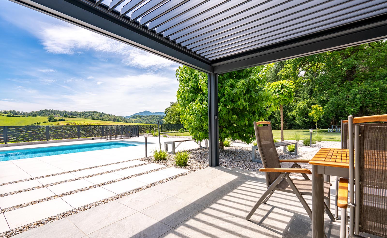 Bioklimatska pergola Misteral na terasi, združuje eleganco in funkcionalnost Moderna bioklimatska pergola Misteral na prostorni terasi, ki zagotavlja udobje skozi vse leto.