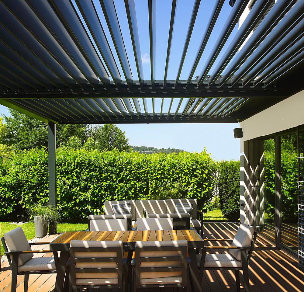 Bioklimatska pergola Misteral v antracit barvi na terasi, ki združuje moderni dizajn in funkcionalnost za udobno bivanje na prostem.